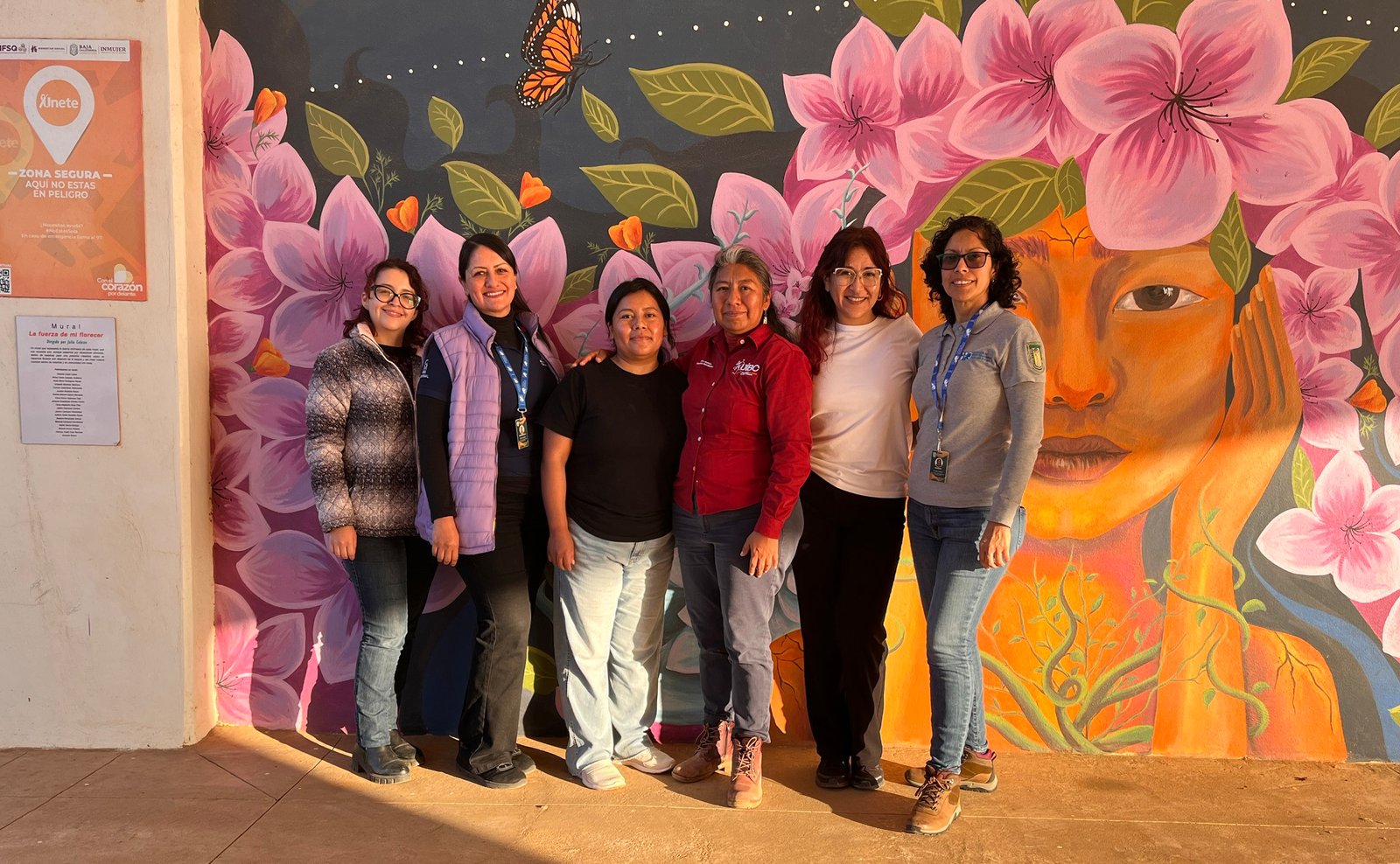 Equipo de divulgación frente a un mural comunitario